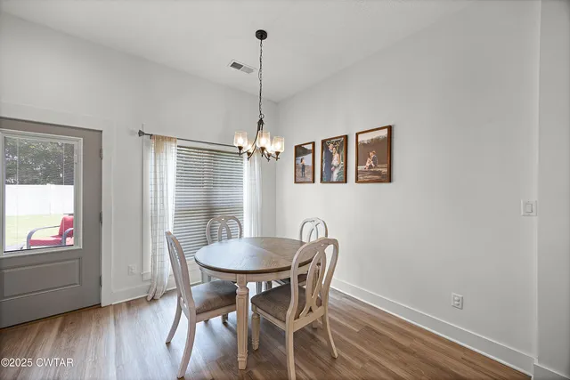 a view of a dining room with furniture a chandelier and wooden floor