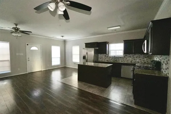 a large kitchen with stainless steel appliances granite countertop a refrigerator a sink dishwasher a stove and a dining table with wooden floor