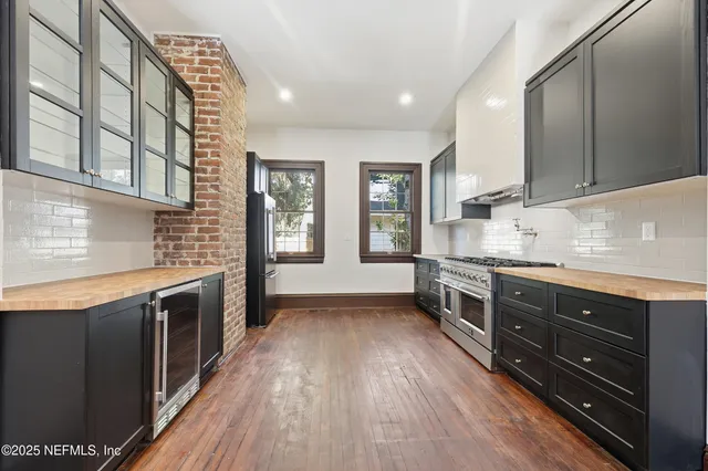 a view of an empty room with wooden floor fireplace and windows