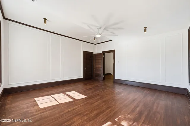 an empty room with wooden floor and ceiling fan