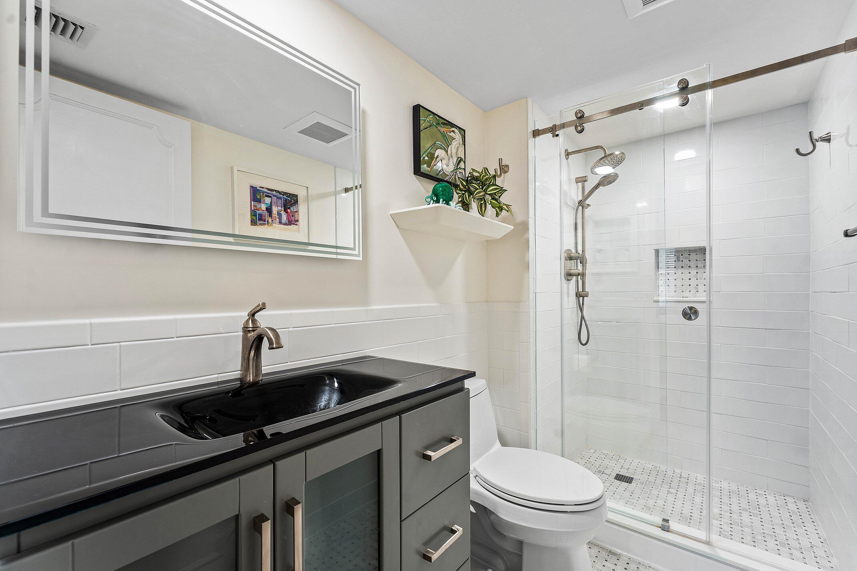 800 East Camino Real, Unit 409 Boca Raton, FL 33432 - Photo 23 of 37 a bathroom with a sink a toilet and shower