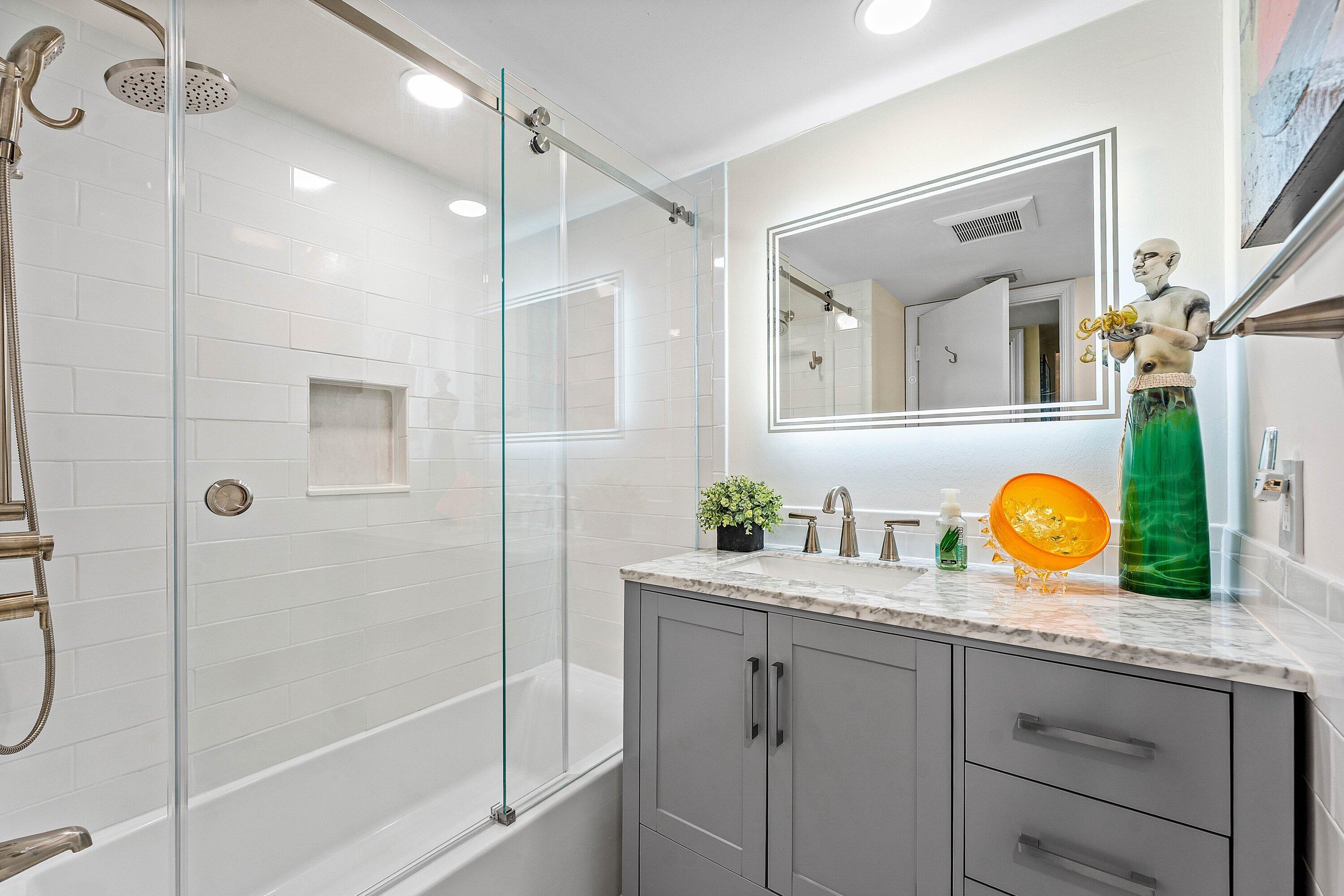 800 East Camino Real, Unit 409 Boca Raton, FL 33432 - Photo 26 of 37 a bathroom with a granite countertop sink a mirror and shower
