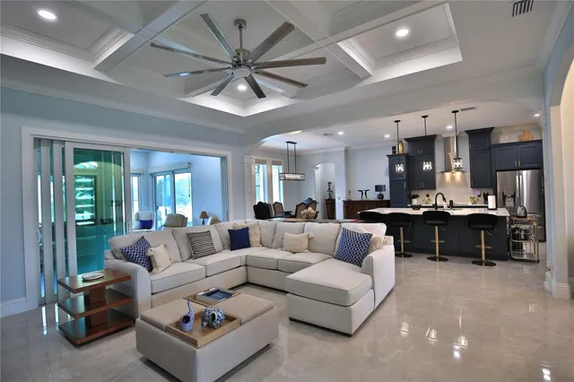 a living room with furniture kitchen area and a chandelier