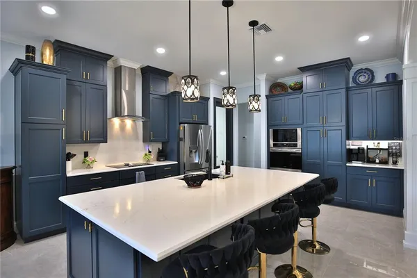 a kitchen with stainless steel appliances kitchen island a table chairs and refrigerator