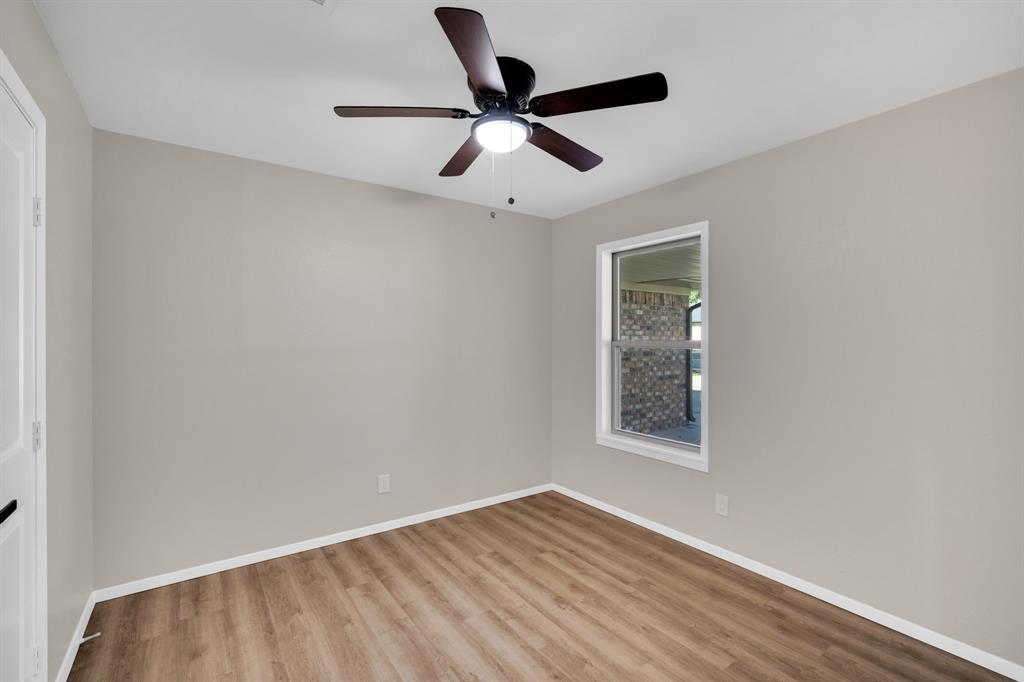 221 North Edgefield Road Waxahachie, TX 75165 - Photo 18 of 27 an empty room with wooden floor ceiling fan and windows