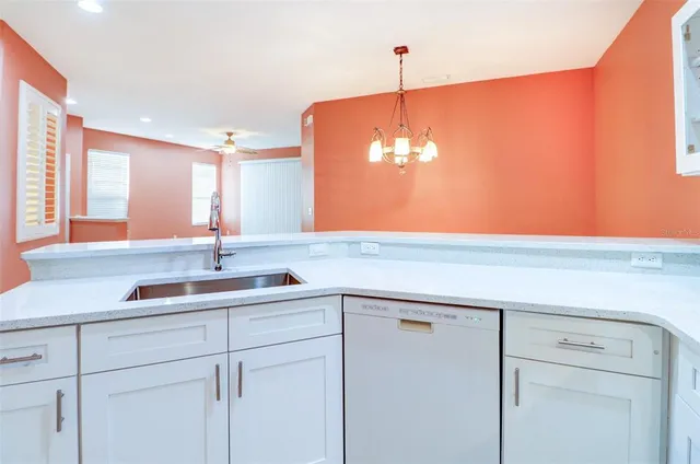 an empty room with a chandelier fan and windows
