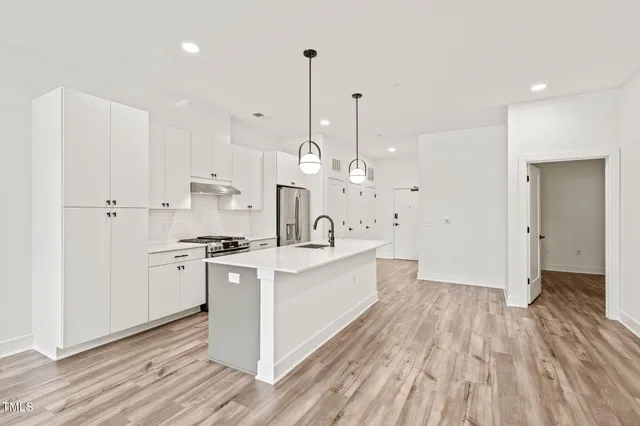 a view of kitchen with stainless steel appliances kitchen island sink stove and living room view