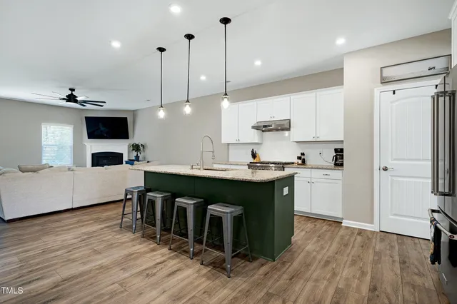 a kitchen with stainless steel appliances granite countertop a refrigerator a oven a sink a stove and white cabinets with wooden floor