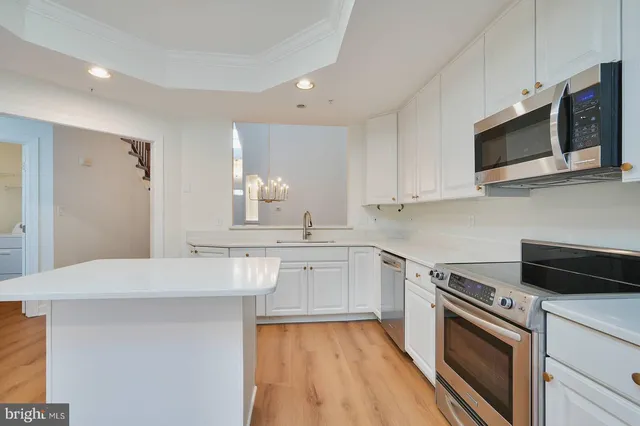 a kitchen with stainless steel appliances white cabinets and a stove top oven