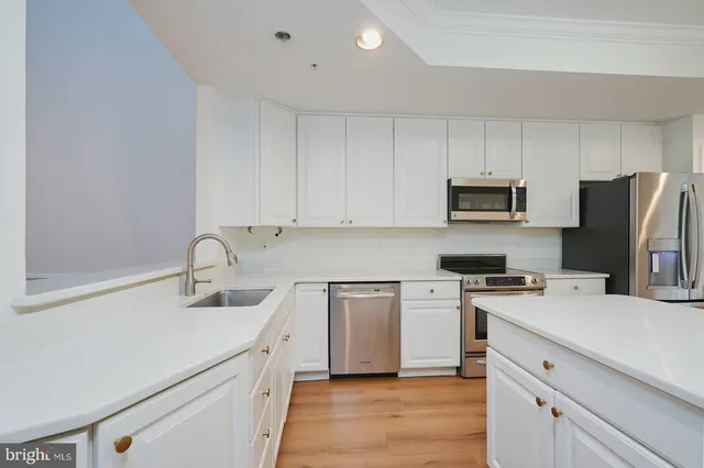 a kitchen with a sink white cabinets and stainless steel appliances