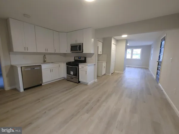 a large kitchen with cabinets wooden floor and stainless steel appliances
