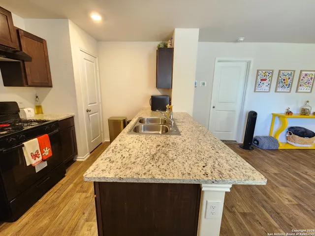 a kitchen with stainless steel appliances kitchen island granite countertop a refrigerator a stove and a sink