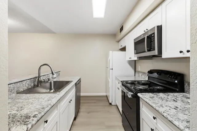 a kitchen with stainless steel appliances granite countertop a sink stove and microwave