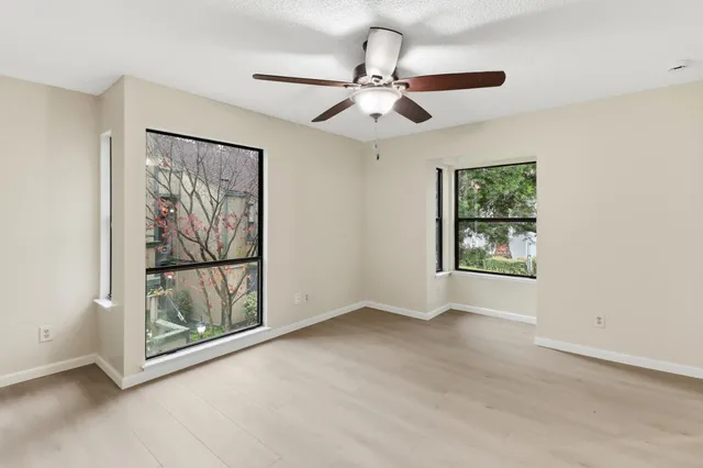 an empty room with windows and fan