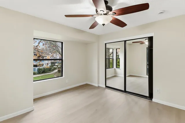an empty room with windows and fan