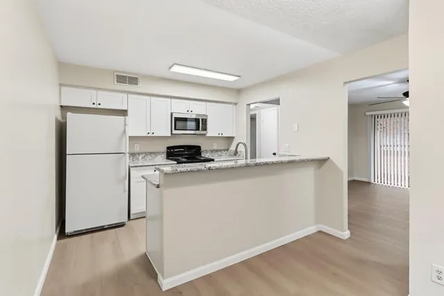 a kitchen with stainless steel appliances granite countertop a refrigerator a stove a sink a microwave a sink and white cabinets