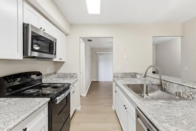 a kitchen with stainless steel appliances granite countertop a sink stove and microwave