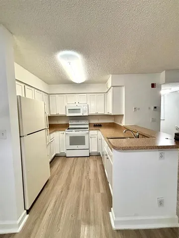 a kitchen with a refrigerator a sink and dishwasher with wooden floor