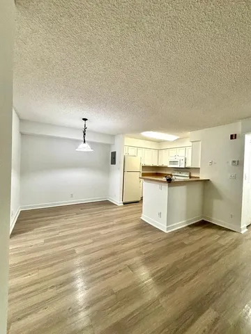 a view of a kitchen with wooden floor and electronic appliances