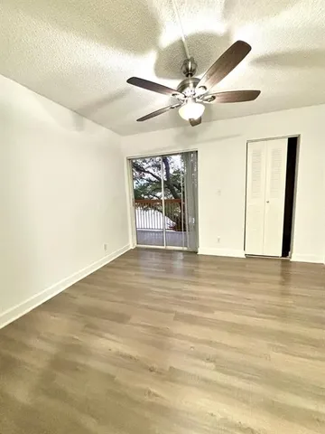 an empty room with wooden floor fan and windows
