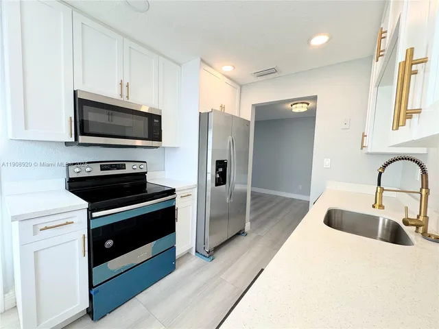 a kitchen with stainless steel appliances a stove a sink and a microwave