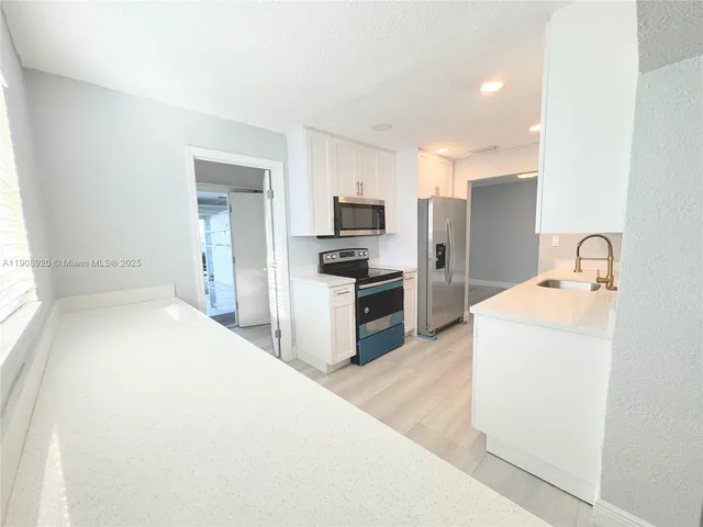 a kitchen with granite countertop a refrigerator and a sink