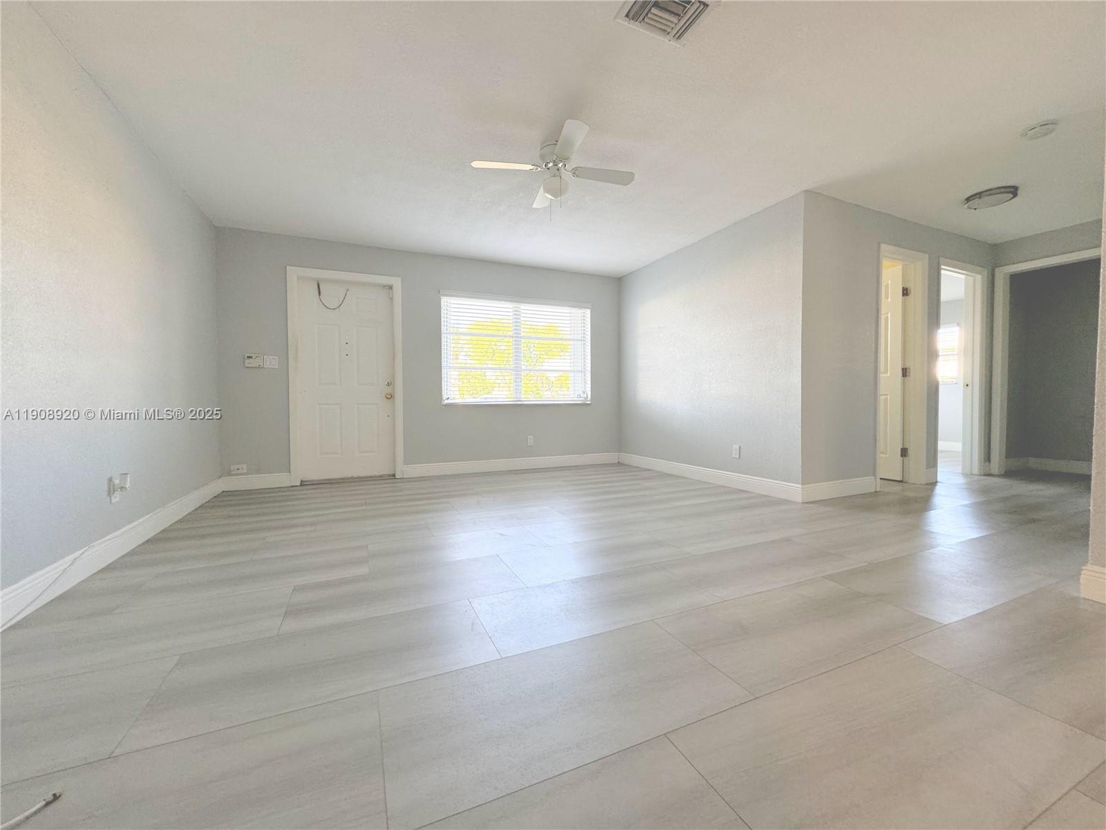 300 Northwest 28th Court Pompano Beach, FL 33064 - Photo 3 of 30 an empty room with wooden floor and windows