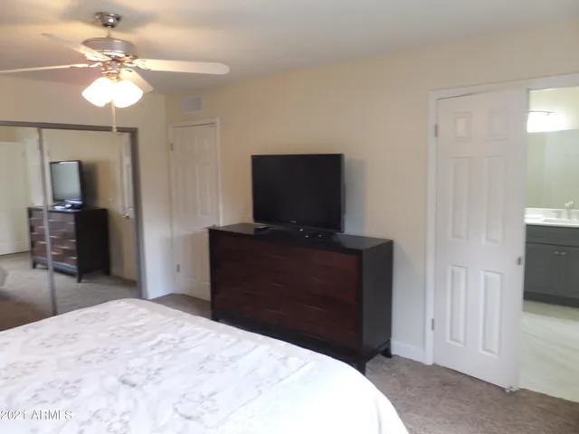 a bedroom with a bed and a flat tv screen on dresser