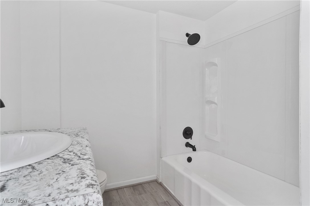646 Brittain Road Akron, OH 44305 - Photo 18 of 36 Bathroom with toilet, a sink, bathing tub / shower combination, wood finished floors, and baseboards