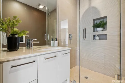 a bathroom with a granite countertop sink a mirror and a shower