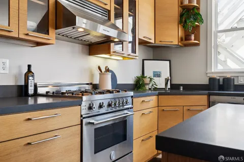 a kitchen with stainless steel appliances granite countertop a stove a sink and a white cabinets