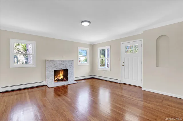 an empty room with windows a fireplace and wooden floor
