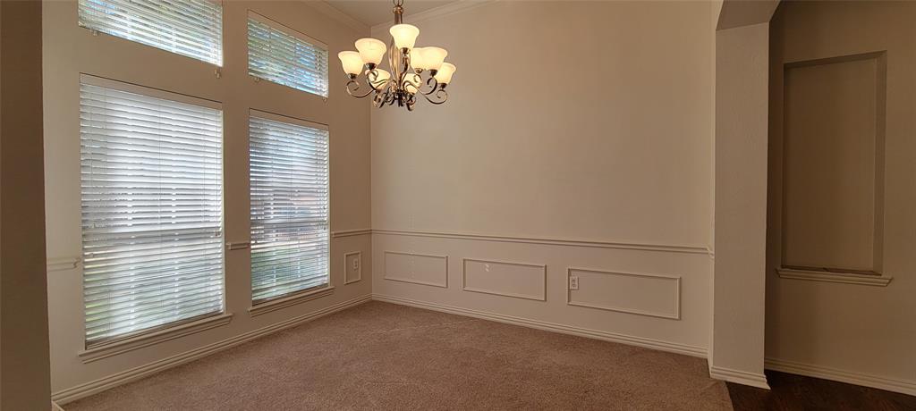 1467 Cattle Baron Court Fairview, TX 75069 - Photo 4 of 32 Carpeted empty room featuring crown molding, a chandelier, a decorative wall, and a wainscoted wall