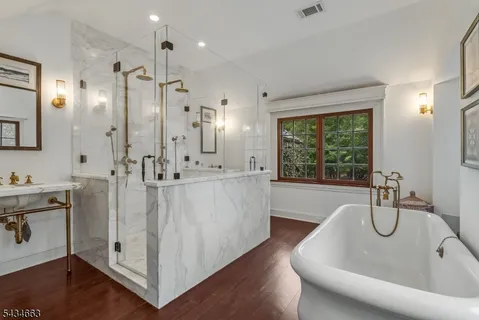 a bathroom with a bathtub a sink a mirror and a shower