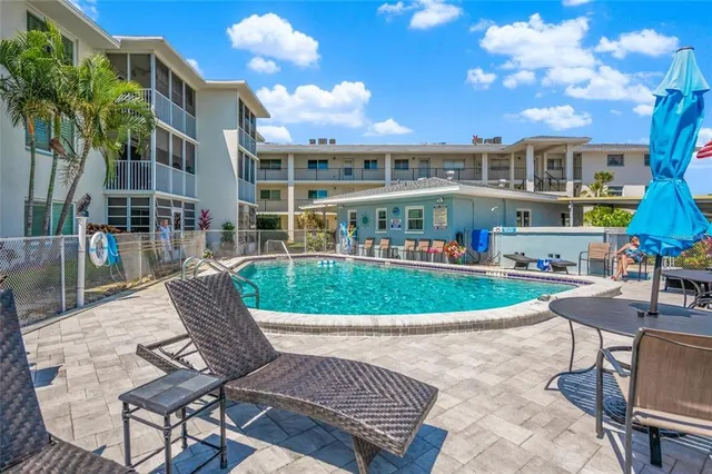a view of a swimming pool with lawn chairs and potted plants
