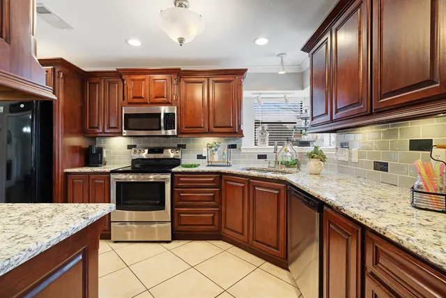 a kitchen with stainless steel appliances granite countertop wooden cabinets a stove a sink and a oven