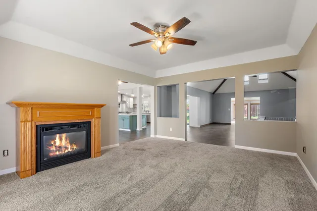 a view of an empty room with a fireplace and a ceiling fan