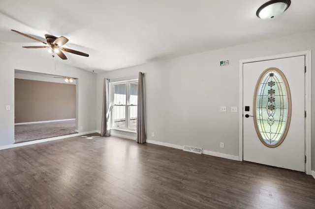 a view of an empty room with wooden floor and window