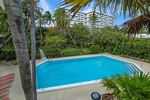 a view of swimming pool with a lawn chairs and palm trees