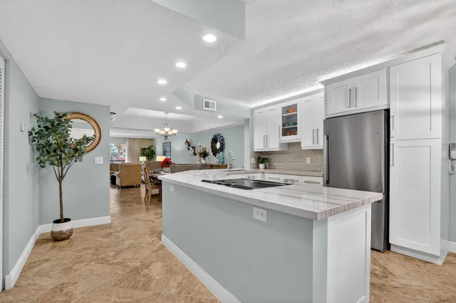 a kitchen with stainless steel appliances granite countertop a sink a stove a refrigerator and a dining table