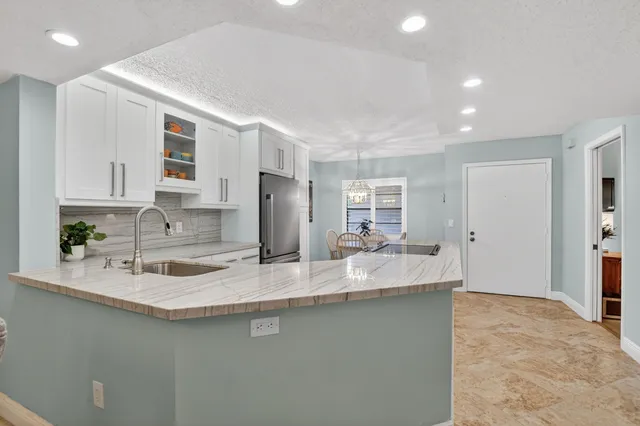 a kitchen with stainless steel appliances granite countertop a sink a stove a refrigerator and a dining table