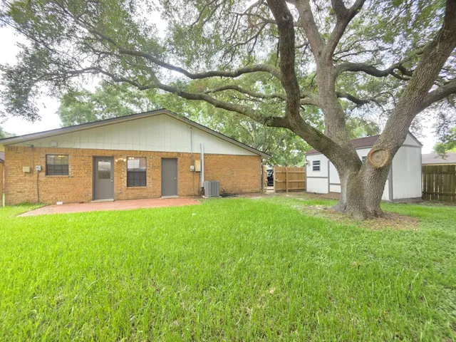 a view of a yard in front of a house with large trees