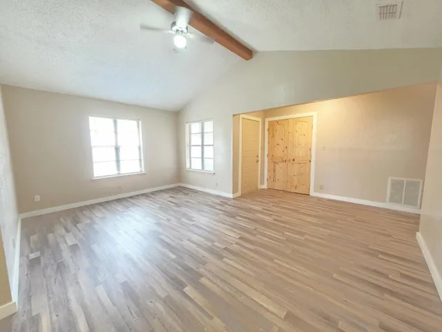 an empty room with wooden floor and windows
