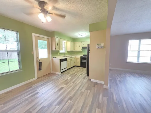 a view of a kitchen with wooden floor a sink a refrigerator and window