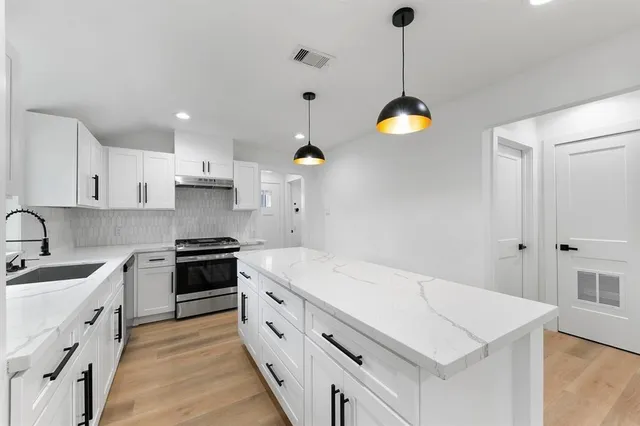 a kitchen with stainless steel appliances granite countertop a sink a stove and a refrigerator