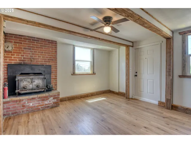 a view of an empty room with wooden floor fireplace and a window