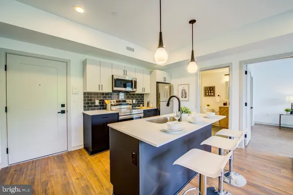a open kitchen with stainless steel appliances granite countertop a stove a sink dishwasher a refrigerator with a dining table and chairs with wooden floor