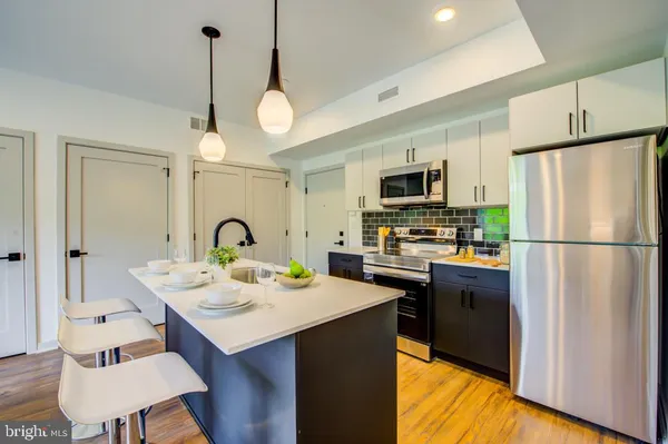a kitchen with stainless steel appliances granite countertop a refrigerator a stove a sink dishwasher a dining table and chairs with wooden floor