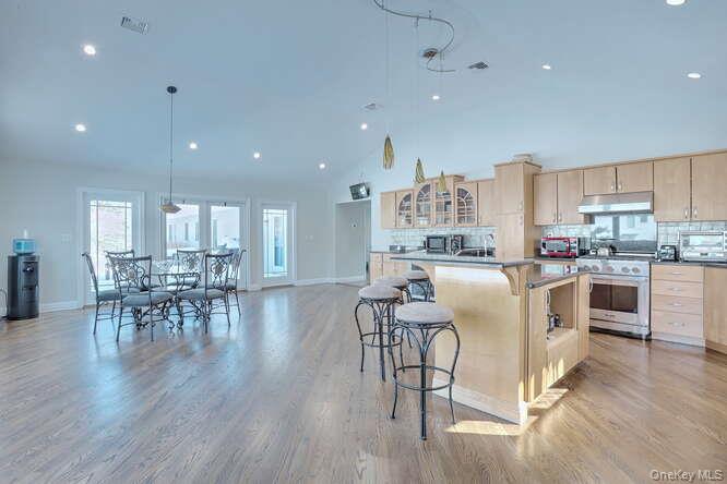 89 Spook Rock Road Suffern, NY 10901 - Photo 14 of 42 a kitchen with stainless steel appliances granite countertop a stove a refrigerator a kitchen island a dining table and chairs with wooden floor
