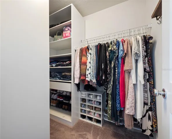 a view of walk in closet with clothes and shoes